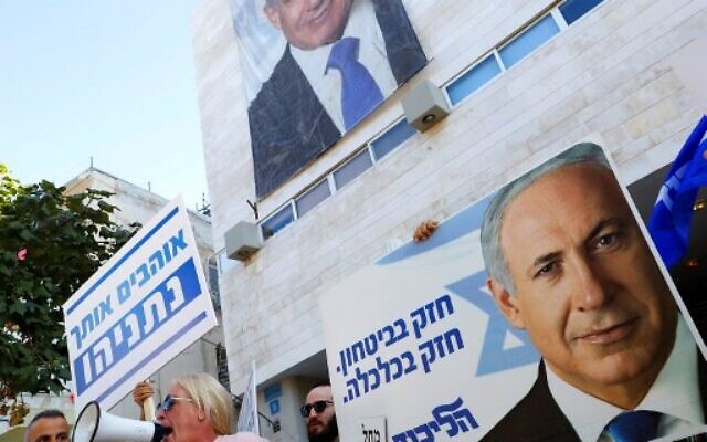 Les partisans du Premier ministre Benjamin Netanyahu scandent des slogans et brandissent des panneaux pour le soutenir lors d'une contre-manifestation organisée aux abords du siège du parti du Likud à Tel Aviv, alors que des Travaillistes se sont rassemblés à proximité contre lui, le 22 novembre 2019 (Crédit : Jack Guez/AFP)