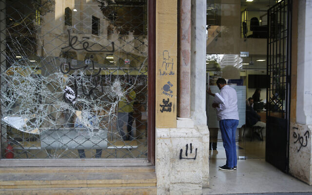 Un client entre dans une banque à la vitrine brisée après des manifestations anti-gouvernement, à Beyrouth, au Liban, le 1er novembre 2019. (Crédit : AP Photo/Hussein Malla)