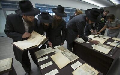 Des visiteurs examinent des livres avant la visite de Vladimir Poutine à la bibliothèque de la famille Schneerson de rabbins hassidiques au Musée juif de Moscou, le 13 juin 2013. (Crédit : AP Photo/Alexander Zemlianichenko)