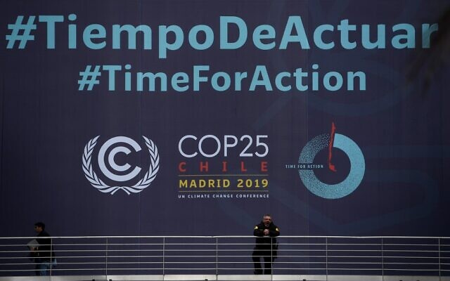 Un garde de sécurité devant la banderole du sommet COP25 sur le climat "Time for Action", au centre de conférence IFEMA de Madrid, le 30 novembre 2019, où le sommet se tiendra du 2 au 13 décembre 2019. (Crédit : Pierre-Philippe Marcou/AFP)