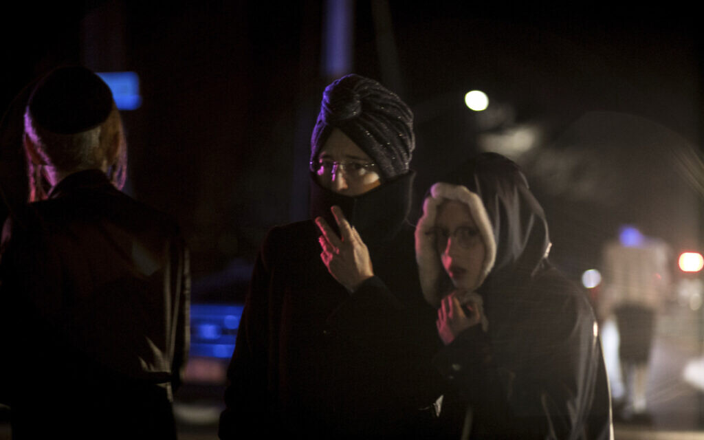 Des passants, dont des résidents juifs orthodoxes, se tiennent au coin de Forshay Road à Monsey, New York, le 29 décembre 2019, en bas de la rue où s'est produit un massacre à coups de couteau la veille, lors d'une célébration de Hanoukka. (Crédit : AP Photo/Allyse Pulliam)