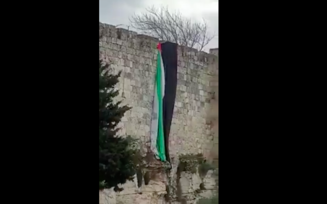 Capture d'écran d'une vidéo montrant le retrait d'un drapeau géant des murs de la Vieille Ville de Jérusalem. (Crédit : Twitter)