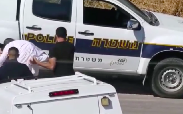 Capture d'écran d'une vidéo où l'on voit le policier attraper un manifestant ultra-orthodoxe par les papillotes. (Crédit : Facebook)