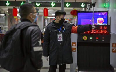 Un agent de sécurité dirige un homme vers une caméra thermique à une station de métro à Pékin, le mercredi 29 janvier 2020.  (AP Photo/Mark Schiefelbein)