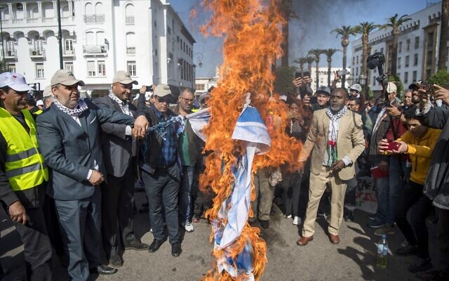 Des Marocains brûlent le drapeau israélien lors d'une manifestation contre le plan de paix américain pour le Moyen Orient dans la capitale Rabat, le 9 février 2020. (Crédit :  FADEL SENNA / AFP)