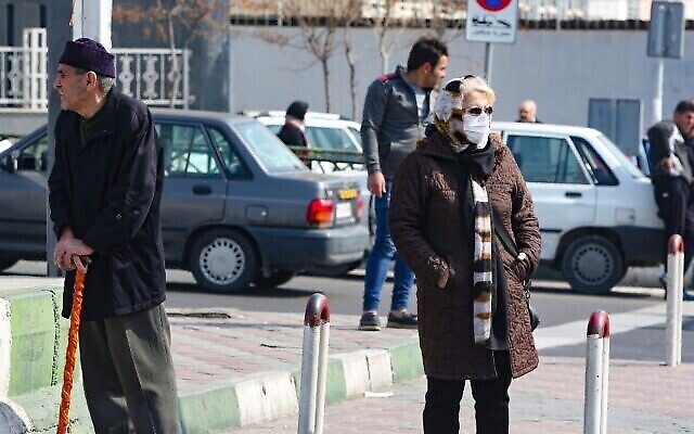 Une Iranienne portant un masque de protection et des gants, dans une rue animée de la capitale Téhéran, le 22 février 2020. (Crédit : ATTA KENARE / AFP)