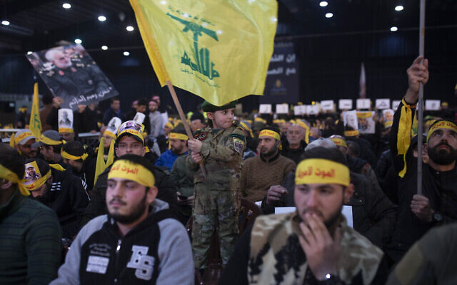 Un enfant en tenue militaire agite le drapeau du Hezbollah alors que des partisans du chef du groupe, Sayyed Hassan Nasrallah, attendent son discours télévisé dans une banlieue sud de Beyrouth, au Liban, le dimanche 5 janvier 2020, suite à l'attaque aérienne américaine en Irak qui a tué le général des Gardiens de la révolution iraniens Qassem Soleimani. (AP Photo/Maya Alleruzzo)
