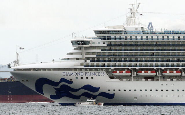 Un petit bateau navigue aux côtés du navire de croisière Diamond Princess, qui a posé l'ancre au port de Yokohama, près de Tokyo, au Japon, le 4 février 2020 (Crédit : Eugene Hoshiko/AP)