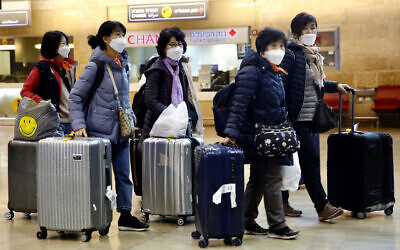 Des touristes coréens portent des masques de protection en attendant leur vol, à l'aéroport Ben Gurion près de Tel Aviv, Israël, le 24 février 2020. (Crédit : AP Photo/Ariel Schalit)