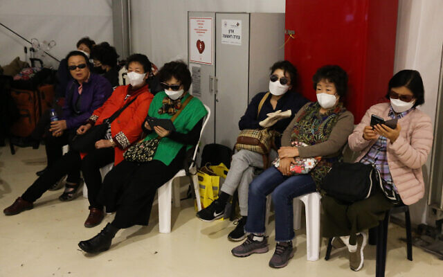 Des touristes sud-coréens forcés de quitter Israël portent des masques en attendant un vol dans une zone d'isolement à l'aéroport international Ben Gurion le 24 février 2020. (Crédit : Flash90)