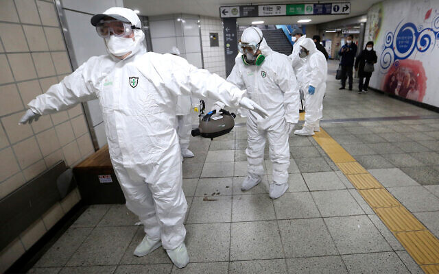 Des travailleurs portant leur tenue de protection aident à nettoyer leurs équipements respectifs après la désinfection contre le coronavirus dans une station du métro de Séoul, en Corée du Sud, le 21 février 2020. (Crédit : AP Photo/Ahn Young-joon)