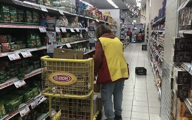 Une employée d'Osem remplit les rayons d'un supermarché Rami Levy à Jérusalem, le 20 février 2020. (Crédit : Sue Surkes/Times of Israel)