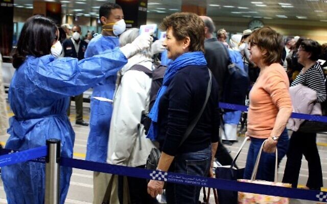Des professionnels de santé égyptiens vérifient la température corporelle de touristes français à leur arrivée à l'aéroport International de Louxor, à environ 680 km au sud du Caire, le 8 mars 2020. (Crédit : AFP)