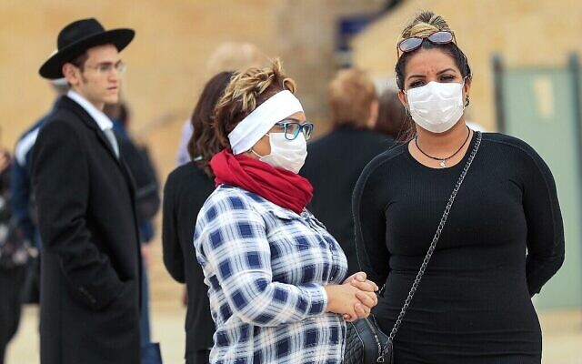 Des femmes portant des masques de protection visitent le mur Occidental pratiquement désert dans la Vieille Ville de Jérusalem le 12 mars 2020, après qu'Israël a imposé certaines des restrictions les plus strictes au monde pour endiguer le nouveau coronavirus. (Emmanuel Dunand/AFP)