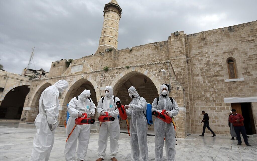 Des travailleurs palestiniens portant des équipements de protection se préparent à désinfecter les murs de la mosquée al-Omari, en prévention de la propagation du coronavirus COVID-19, dans la ville de Gaza, le 12 mars 2020. (Crédit : MAHMUD HAMS / AFP)