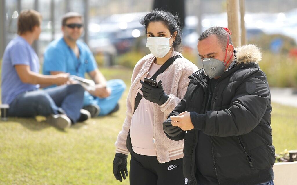 Des personnes portant des masques de protection entrent dans l'hôpital universitaire Samson Assuta à Ashdod, le 16 mars 2020. (Crédit : JACK GUEZ / AFP)