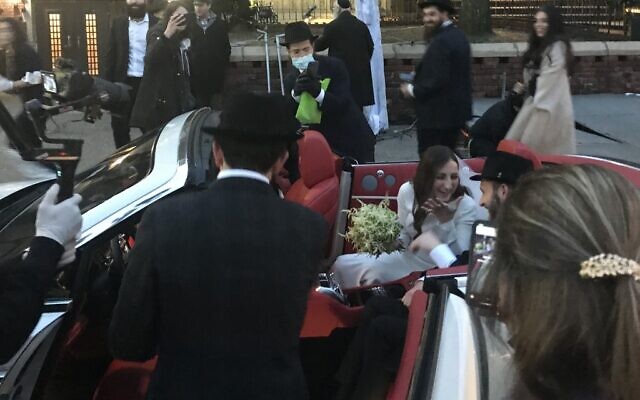Le marié JJ Deitch et sa femme, Fraida, montent dans un cabriolet alors que les gens se rassemblent pour leur mariage à Brooklyn, le 19 mars 2020 (Crédit : Maggy DONALDSON / AFP)