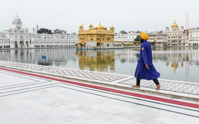 Un bénévole Sikh sewadar marche dans le Temple Doré désert lors du premier des 21 jours de confinement imposé par le gouvernement comme mesure préventive contre le coronavirus COVID-19 à Amritsar le 25 mars 2020. (Photo par NARINDER NANU / AFP)