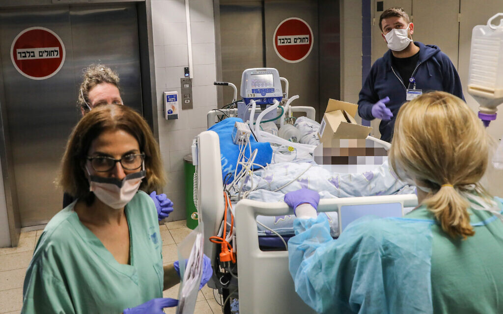 Des membres du personnel de l'hôpital Ichilov de Tel Aviv déplacent un patient vers un nouveau service, le 22 mars 2020. (Crédit : Yossi Zamir / Flash90)