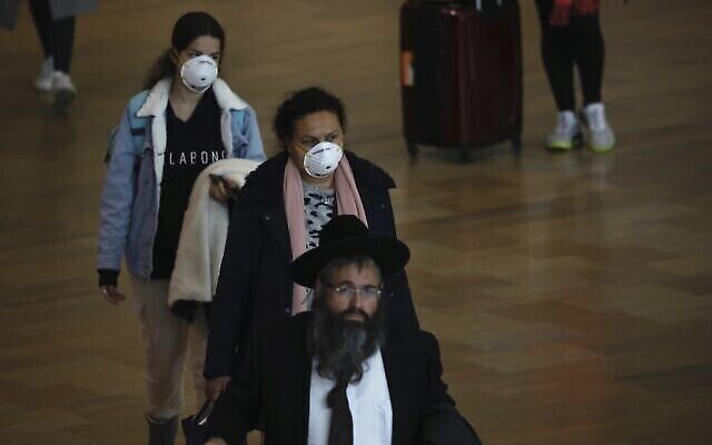 Des passagers portent des masques à l'aéroport Ben Gourion, près de Tel Aviv, en Israël, le 10 mars 2020. (Crédit : AP Photo / Ariel Schalit)