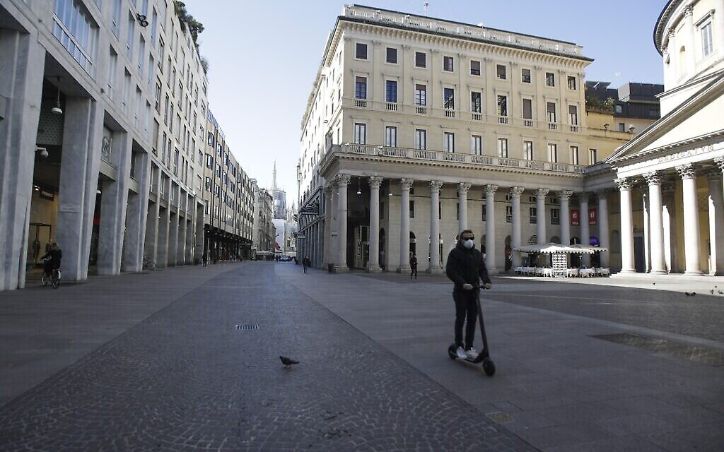Un homme portant un masque sur une trottinette à Milan, en Italie, le 11 mars 2020. (Crédit : AP Photo/Luca Bruno)