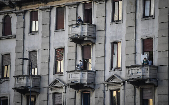 Des gens sur leur balcon pour jouer de la musique ou chanter lors d'un flash mob lancé dans toute l'Italie pour rapprocher les gens et essayer de faire face à la quarantaine généralisée, à Milan, en Italie, le 13 mars 2020. (Crédit : Claudio Furlan/LaPresse via AP)