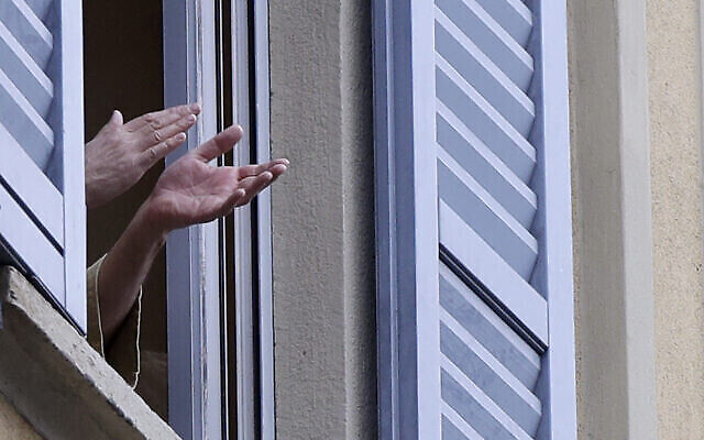 Un homme applaudit depuis sa fenêtre, à Milan, en Italie, le 14 mars 2020. (Crédit : AP Photo/Luca Bruno)