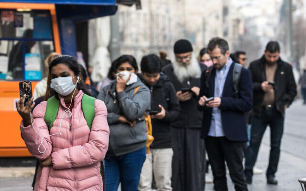 Des Israéliens portant un masque par crainte du coronavirus font la queue devant la poste centrale du centre ville de Jérusalem le 15 mars 2020 (Crédit : Olivier Fitoussi/Flash90)