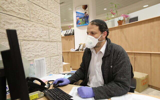Un employé de banque muni d'un masque de protection contre le coronavirus, à Jérusalem, le 17 mars 2020. (Crédit : Yossef Zamir/Flash90)