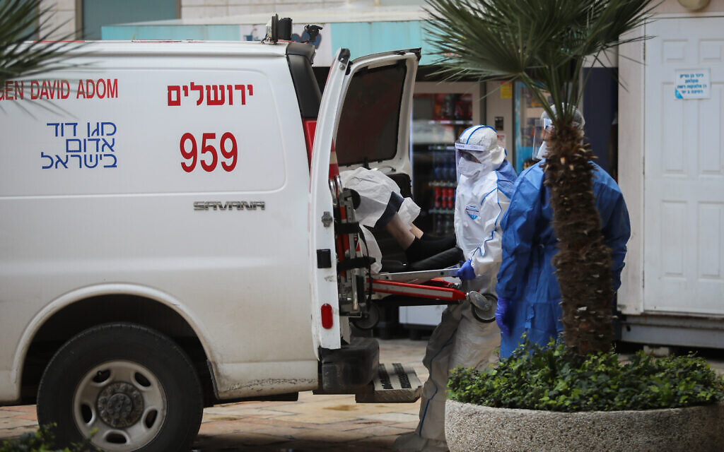 Des ambulanciers portent un équipement de protection en mesure préventive contre le coronavirus alors qu'ils évacuent une femme qui pourrait avoir attrapé le COVID-19 à l'hôpital Hadassah Ein Kerem de Jérusalem, le 22 mars 2020 (Crédit : Flash90)