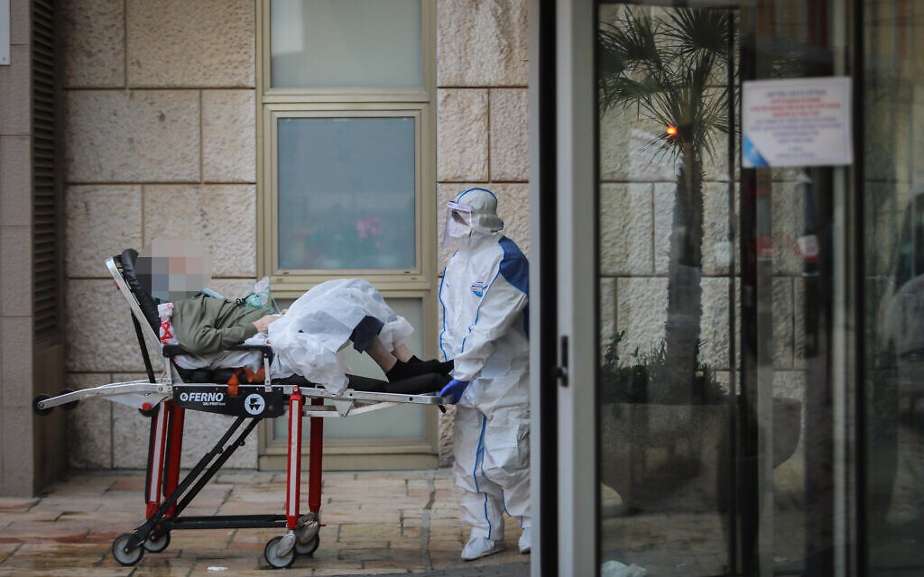 Des travailleurs du Magen David Adom portant des vêtements de protection comme mesure préventive contre le coronavirus, transfèrent une femme à l'hôpital Hadassah Ein Karem, à Jérusalem, le 22 mars 2020. (Crédit : Flash90)