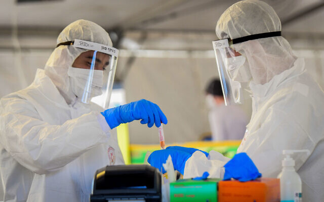 Des membres de l'équipe médicale du Magen David Adom, portant des équipements de protection, manipulent un échantillon de test de Coronavirus, à Tel-Aviv, le 22 mars 2020. (Crédit : Flash90)