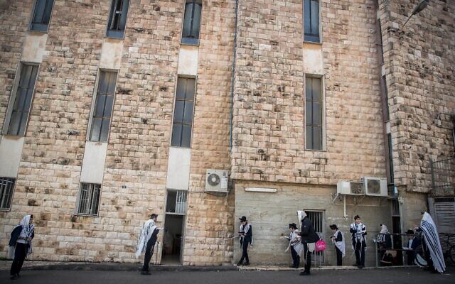 Des hommes prient à l'extérieur d'une synagogue à Bayit Vegan, Jérusalem, le 22 mars 2020. (Yonatan Sindel/Flash 90)