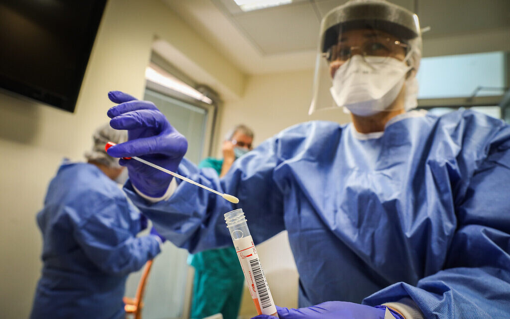 Les membres de l'équipe médicale d'Hadassah Ein Kerem, portant des équipements de protection, manipulent un échantillon de test de Coronavirus, à Jérusalem le 24 mars 2020. (Crédit : Yossi Zamir/Flash90)