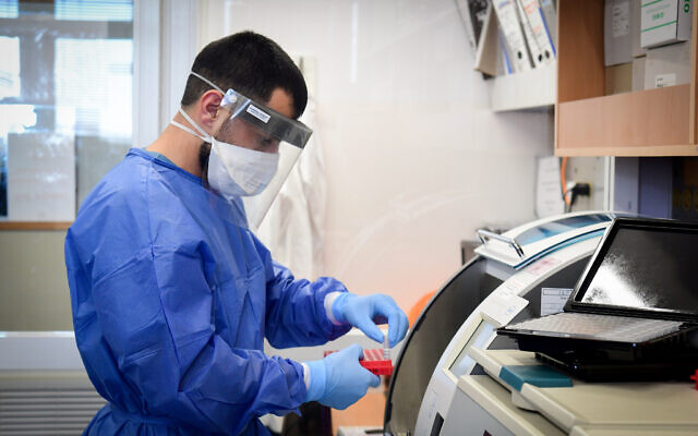 Un des membres de l'équipe médicale de l'hôpital Barzilay, dans la ville d'Ashkelon, au sud d'Israël, porte un équipement de protection, alors qu'il manipule un échantillon de coronavirus, le 29 mars 2020. (Flash90)