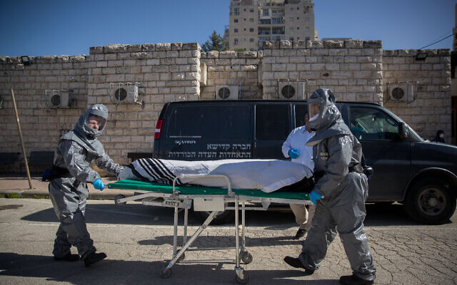 Illustration : Des employés de pompes funèbres portant des vêtements de protection transportent le corps d'un patient décédé du coronavirus (COVID-19), au Shamgar Funeral Home à Jérusalem, le 29 mars 2020. (Yonatan Sindel/Flash90)