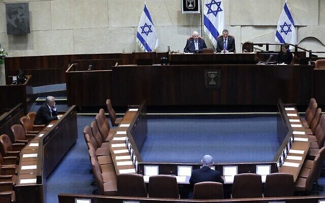 Un plénum presque vide, en raison des restrictions contre le coronavirus, lors de la prestation de serment de la 23e Knesset, le 16 mars 2020. À gauche, Benny Gantz. Au centre, de dos, Benjamin Netanyahu. (Gideon Sharon/ Porte-parole de la Knesset)