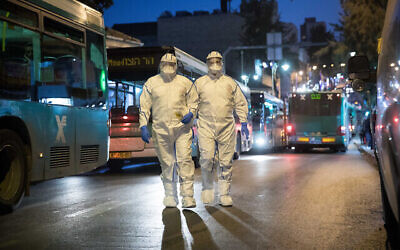 Des soignants portent des tenues de protection par mesure de précaution alors qu'ils s'apprêtent à examiner un patient présentant des symptômes du Covid-19, à Jérusalem, le 16 mars 2020. (Crédit : Yonatan Sindel/ Flash90)