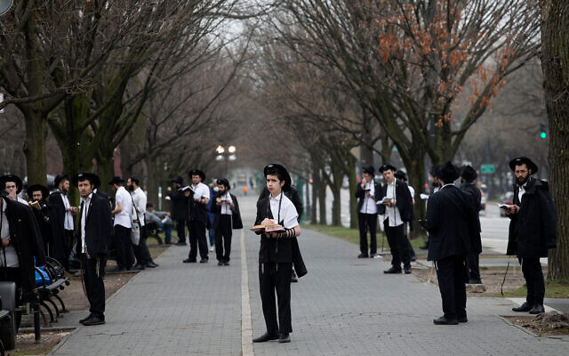 Des hommes juifs respectent la "distanciation sociale" alors qu'ils prient devant le siège mondial du mouvement Habad Loubavitch à Brooklyn, New York, le 20 mars 2020. (AP/Mark Lennihan)