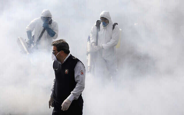 Des pompiers iraniens désinfectent les rues dans la capitale Téhéran afin de tenter de ralentir la propagation rapide du coronavirus, le 13 mars 2020. (AP Photo/Vahid Salemi)