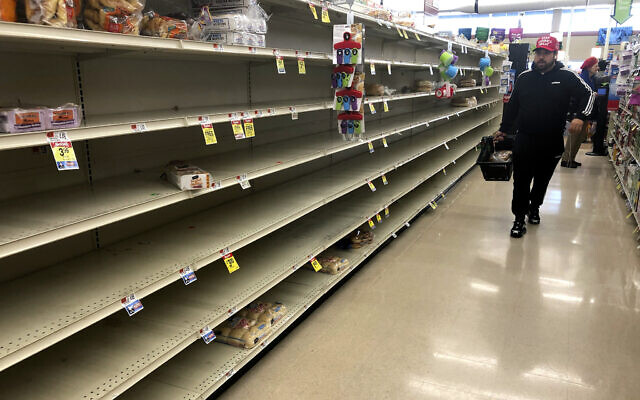 Un client passe devant les étagères vides où le pain est normalement proposé à la vente dans un supermarché, le dimanche 15 mars 2020 à Boston. (AP Photo/Steven Senne)
