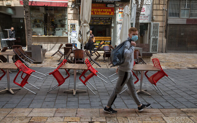 Un homme portant un masque passe à côté de restaurants fermés à Jérusalem, le 15 mars 2020. (Nati Shohat/Flash90)