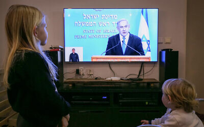 Des enfants israéliens regardent le Premier ministre Benjamin Netanyahu en train de faire une conférence de presse sur les nouvelles restrictions gouvernementales imposées au public concernant le COVID-19 le 19 mars 2020. (Photo par Chen Leopold/Flash90)