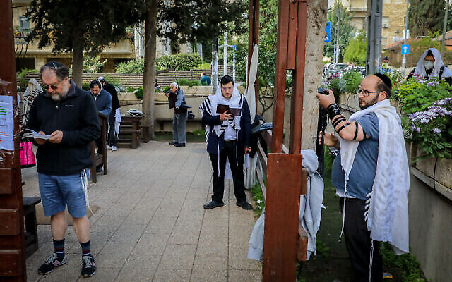 Des hommes juifs prient devant une synagogue dans le quartier de Nachlaot à Jérusalem le 25 mars 2020. (Photo par Yossi Zamir/Flash90)