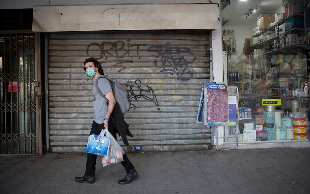 Un homme passe devant des magasins et des restaurants fermés à Tel Aviv, le 15 mars 2020. (Miriam Alster/FLASH90)