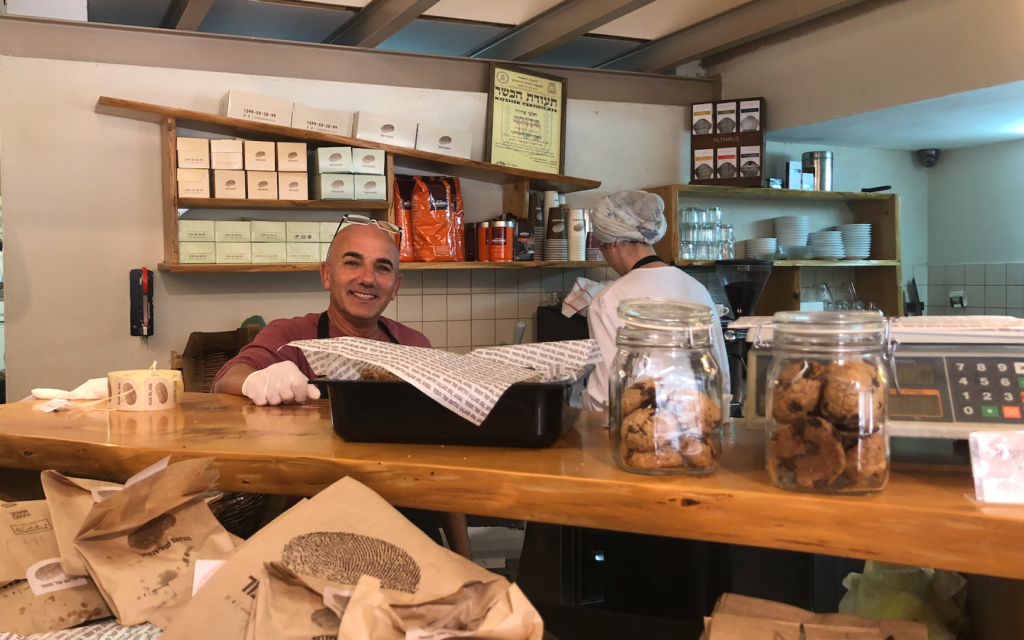 Nissim Naveh au comptoir de la boulangerie Lehem shel Tomer à Arnona, où les clients font la queue pour acheter du pain mais ne peuvent pas s'asseoir pour boire un café, le 15 mars 2020. (Jessica Steinberg/Times of Israel)