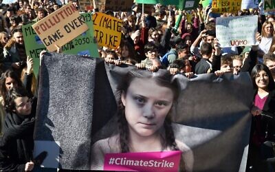 Des manifestants et des étudiants brandissent des panneaux et une bannière montrant l'activiste politique suédoise de 16 ans Greta Thunberg, qui milite contre le réchauffement  et le changement climatiques, lors d'un mouvement de protestation contre le réchauffement global à Rome, le 15 mars 2019 (Crédit :Andreas Solaro/AFP)