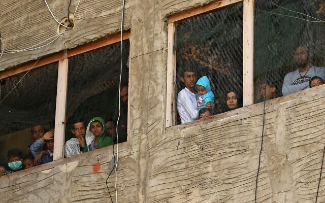 Des réfugiés syriens observent depuis les fenêtres d'un bâtiment en construction qu'ils utilisent comme abri dans la ville de Sidon du sud du Liban, le 17 mars 2020. (Photo par Mahmoud ZAYYAT / AFP)