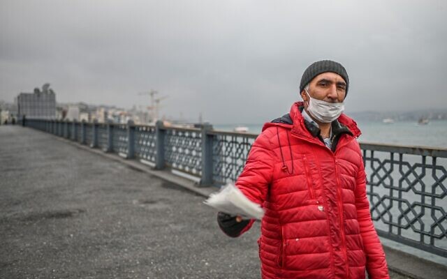 Un vendeur tente de vendre des masques de protection sur le pont vide de Galata le 1 avril 2020 à Istanbul, après que des responsables turcs ont appelé les citoyens à rester à la maison et à respecter les règles de distanciation sociale. (Crédit : Ozan KOSE / AFP)