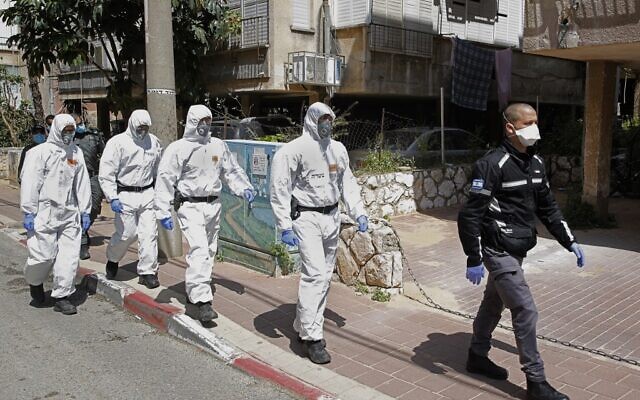 Des policiers israéliens, en tenue de protection, arrivent dans une yeshiva dans la ville israélienne de Bnei Brak le 2 avril 2020, pour s'assurer que les mesures de distanciation sociale imposées par les autorités israéliennes visant à freiner la propagation du nouveau coronavirus sont respectées. (Crédit : JACK GUEZ / AFP)